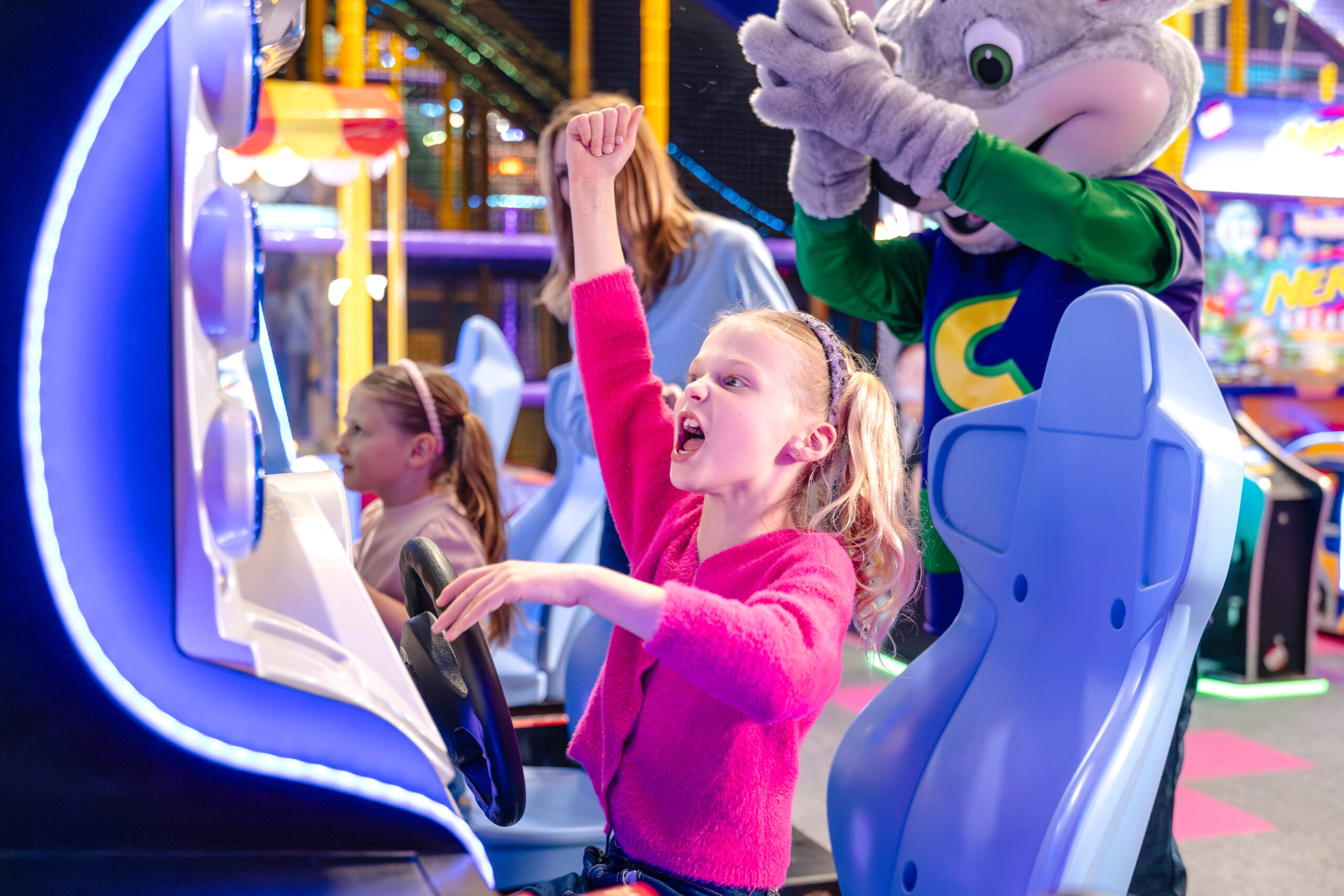A photo of two girls racing on car games in the Chuck E. Cheese games arcade.