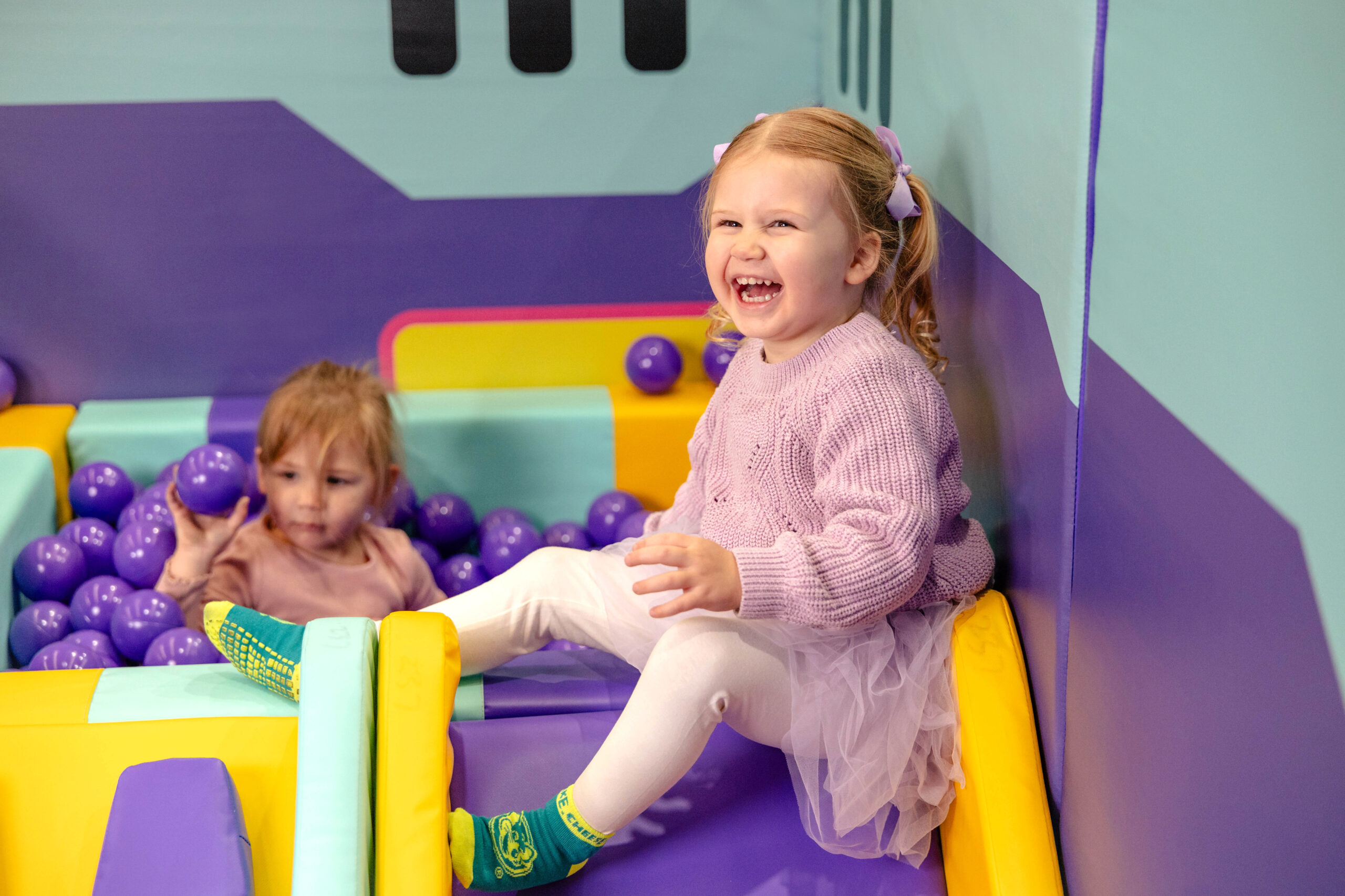A photo of two toddlers in a sensory ball pit in the Chuck E. Cheese toddler zone indoor playground.