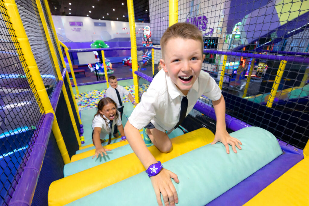 Three boys climbing in the adventure zone after school in their school uniforms.
